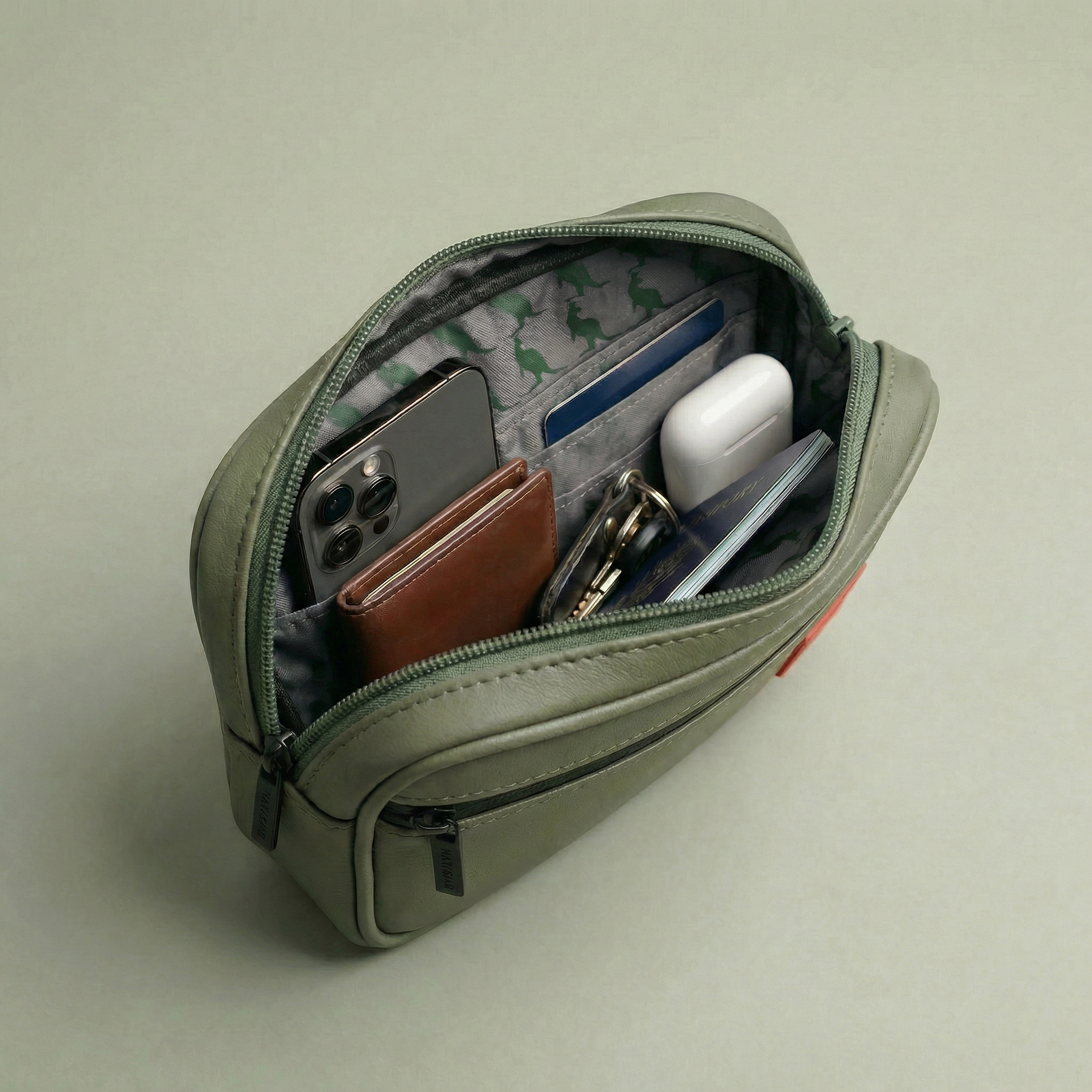 Green zippered pouch with various items on a light gray background Detachable utility pouch with waterproof zipper and logo patch